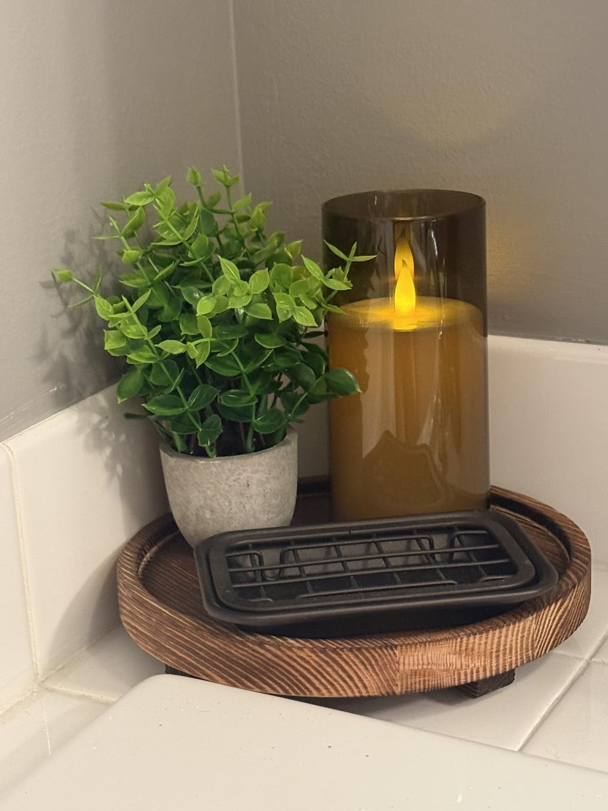 Flameless glass candle styled with a plant on a riser
