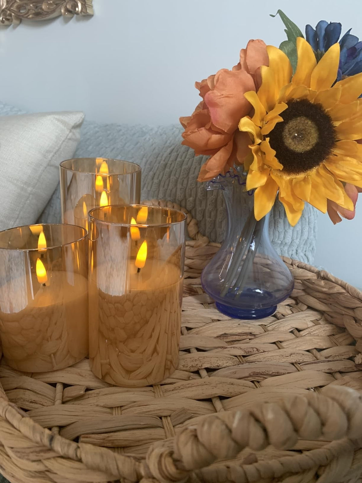 Glass pillar candles with sunflowers on a woven tray