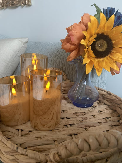 Glass pillar candles with sunflowers on a woven tray