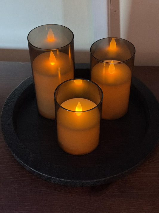 Three flameless glass candles glowing on a black tray