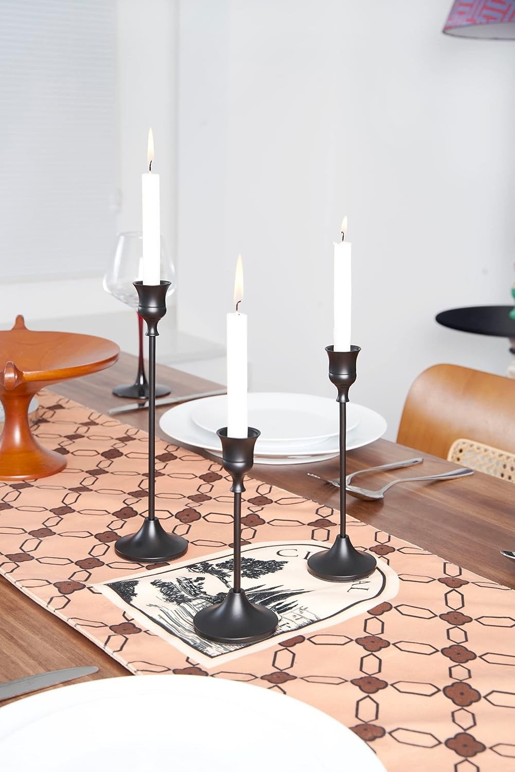 Black bell candle holders on a table runner