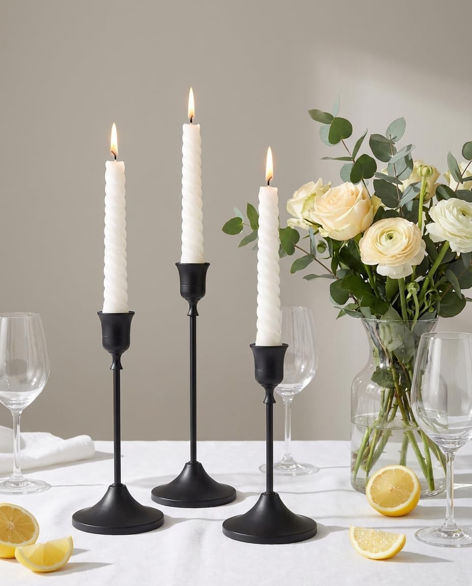 Black taper candle holders with flowers on a white table